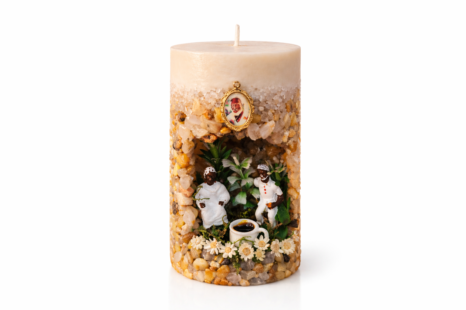 Vela artesanal Gruta dos Pretos Velhos decorada com pedras naturais, miniaturas de Pretos Velhos, flores brancas e xícara de café sobre fundo neutro.