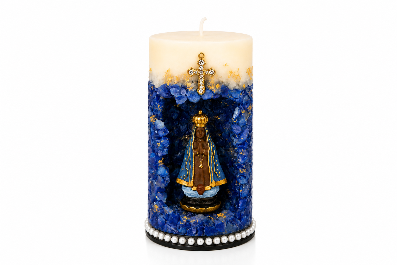 Vela Gruta de Nossa Senhora Aparecida artesanal em tons de azul royal, branco e dourado, com imagem de Nossa Senhora Aparecida posicionada em nicho central decorativo. A peça possui acabamento com cristais azuis, detalhes dourados aplicados manualmente, cruz ornamentada na parte superior e base decorada com pérolas. A fotografia apresenta fundo branco suave, destacando todos os detalhes da vela de forma elegante e profissional.